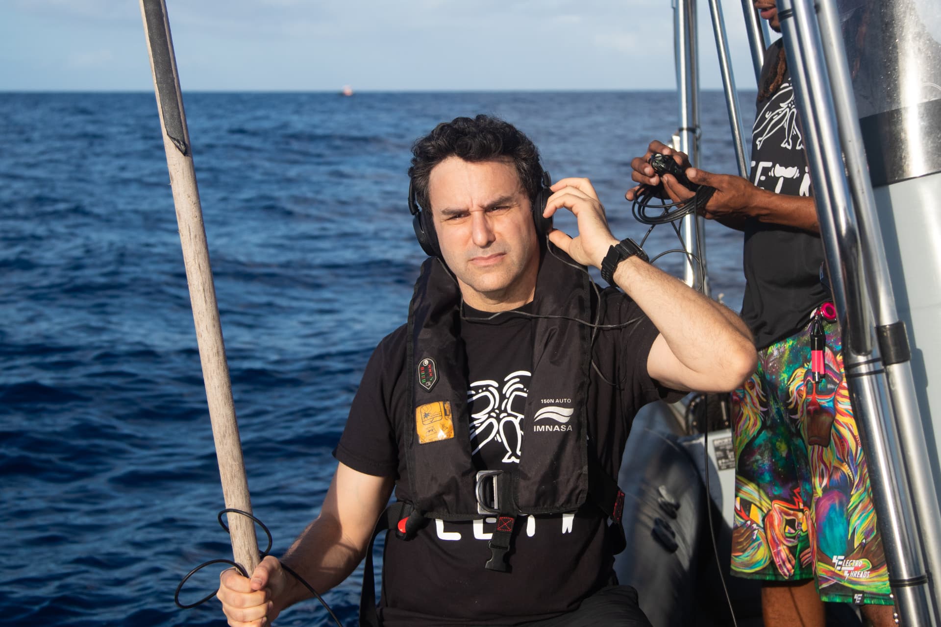 David Gruber wearing headphones on the deck of the research vessel CETI-2, listening to recordings