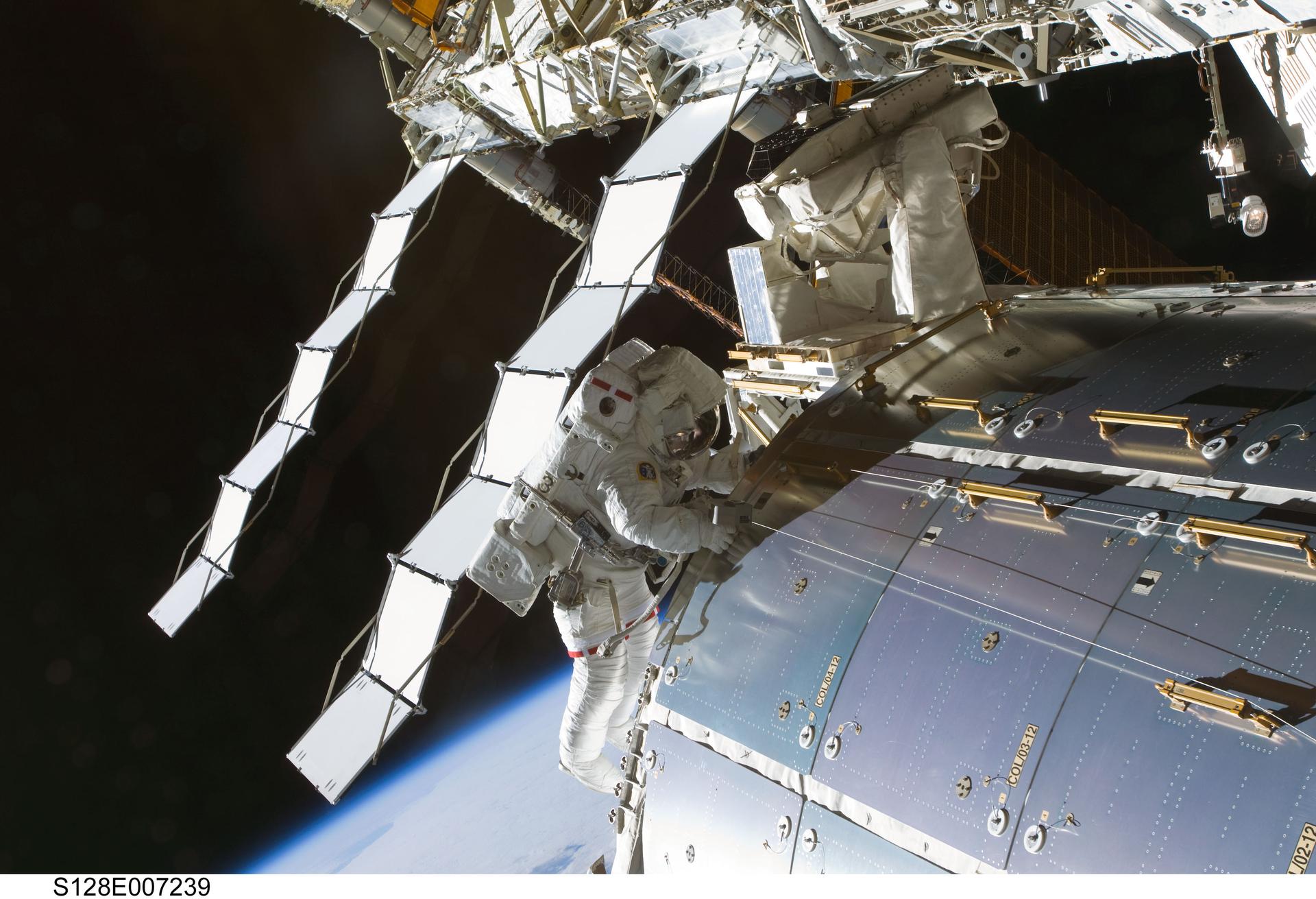 Astronaut Nicole Stott works outside the International Space Station, Earth’s blue limb curving below