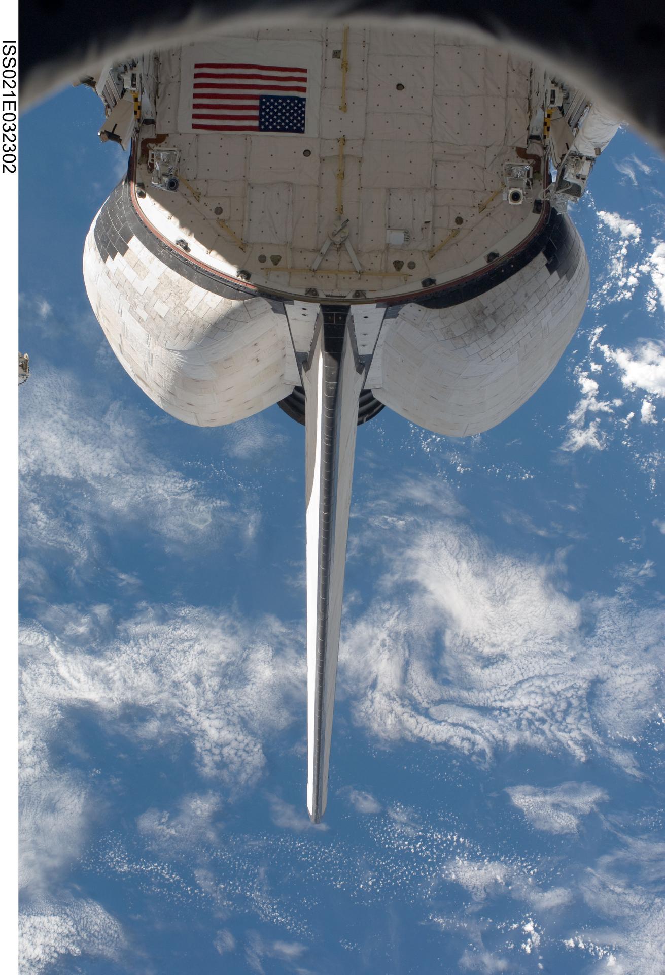 A spacecraft seen from below with Earth and clouds in the background